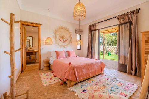 a bedroom with a bed with pink pillows and a mirror at Villa Yakout in Ghazoua