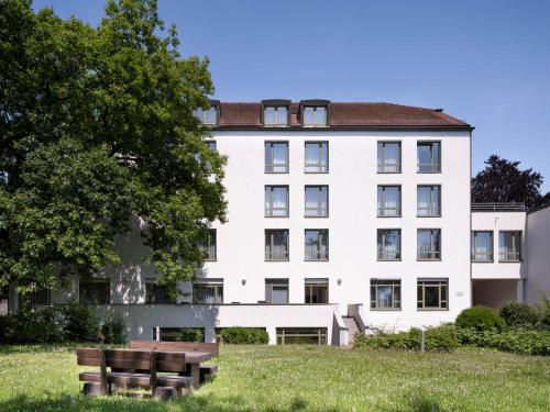 a white building with a bench in front of it at Christkönigshaus in Stuttgart