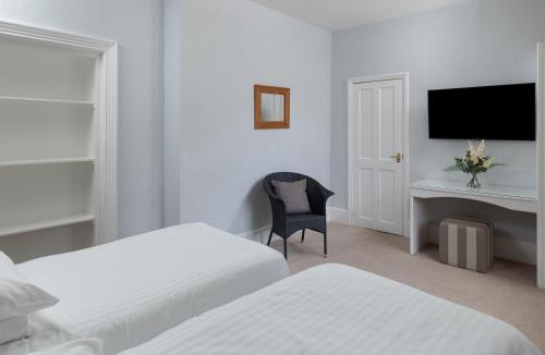 a bedroom with two beds and a desk and a chair at The Hunters Inn in Martinhoe