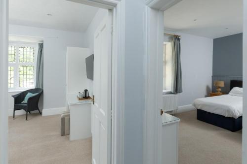 a white bedroom with a bed and a desk at The Hunters Inn in Martinhoe