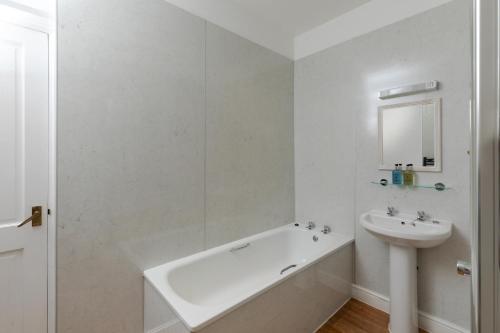 a white bathroom with a tub and a sink at The Hunters Inn in Martinhoe