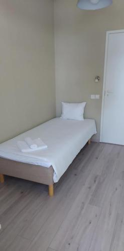 a white bed in a room with a wooden floor at Lainela puhkeküla in Käsmu