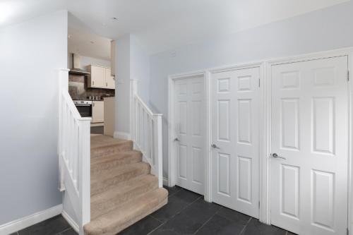 a white hallway with white doors and a staircase at The Hunters Inn in Martinhoe