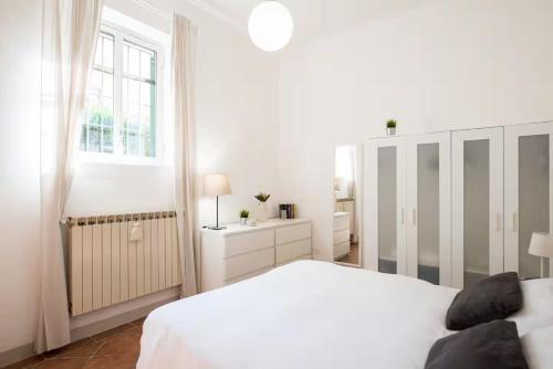 a white bedroom with a white bed and a window at 2 apartments next to a market and Piazza Santa Croce - HomeUnity in Florence