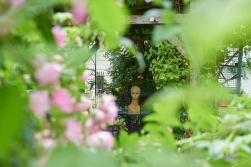 a statue in the middle of a garden with pink flowers at Hametner mit Innviertlerhaus mit Thermenzugang in Bad Hall