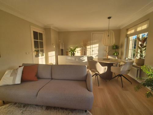 a living room with a couch and a table at Luxe vakantiehuis op de Veluwe met tuin in Barneveld in Barneveld