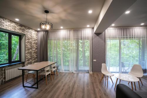 ein Esszimmer mit Tisch und Stühlen und Fenstern in der Unterkunft Khaz Cottage Dilijan in Dilidschan