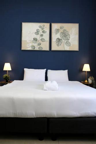 a bedroom with a large white bed with three pictures on the wall at Paris Square Apartments Downtown in Haifa