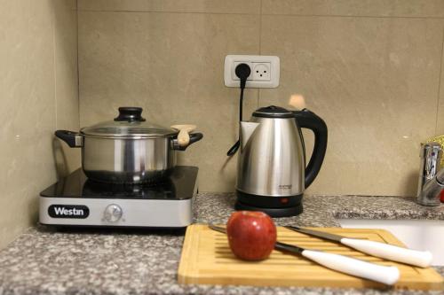a kitchen counter with a pot and an apple on a cutting board at Paris Square Apartments Downtown in Haifa