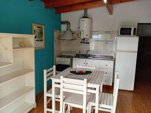 a kitchen with a table and chairs and a refrigerator at Cabañas Silvia Banegas in Santa Rosa de Calamuchita