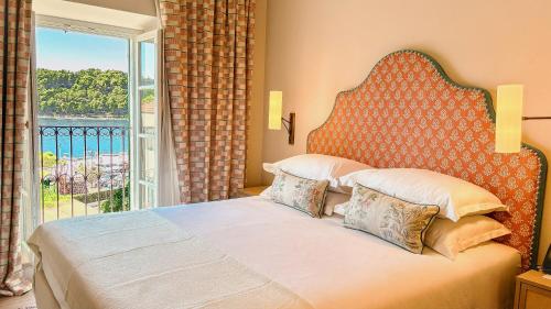 a bedroom with a large bed with a large window at Hotel Supetar in Cavtat