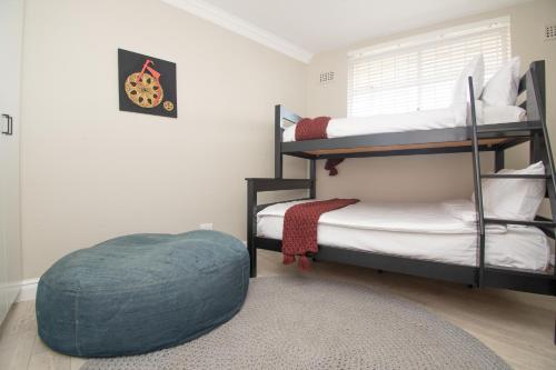 a bedroom with two bunk beds and a blue ottoman at 64 Sea Lodge Umhlanga Rocks in Durban