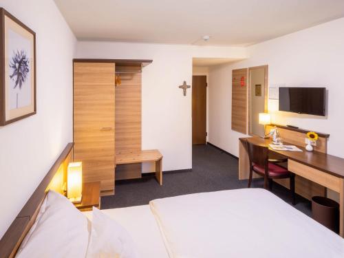 a hotel room with a bed and a desk and a computer at Christkönigshaus in Stuttgart