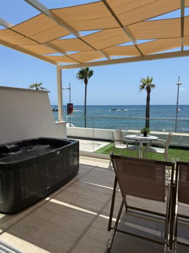 a patio with a hot tub and a table and chairs at Harbour Lights Studio Apartments in Paphos City