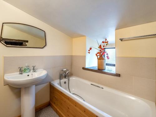 a bathroom with a sink and a bath tub and a mirror at 4 Bed in Longtown 86497 in Llanveynoe