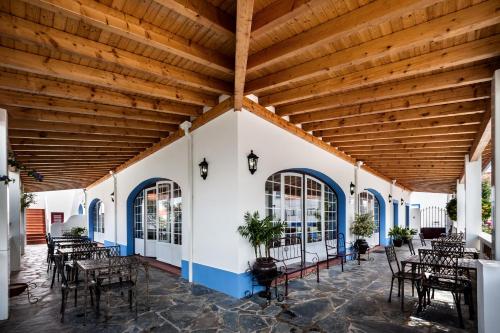 a patio with tables and chairs and a wooden ceiling at Vila Planicie in Monsaraz