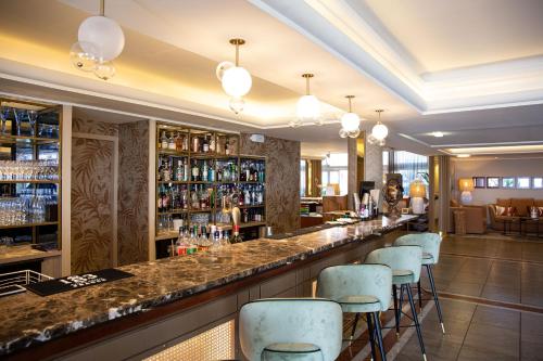 a bar in a hotel with blue bar stools at Grand Hôtel Les Flamants Roses Thalasso & Spa in Canet-en-Roussillon