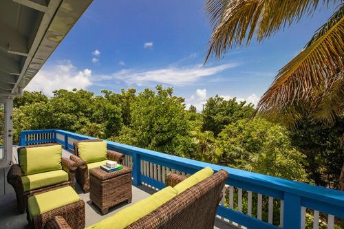 a porch with a couch and chairs on a blue fence at Hideaway Villa 2 Minute walk to Gracebay beach in The Bight Settlements