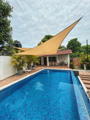 a swimming pool in front of a house with a roof at Escapada a Perla de Mar - ATAMI in Tamanique