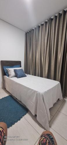 a large bed in a room with a curtain at Quarto individual in Mogi das Cruzes