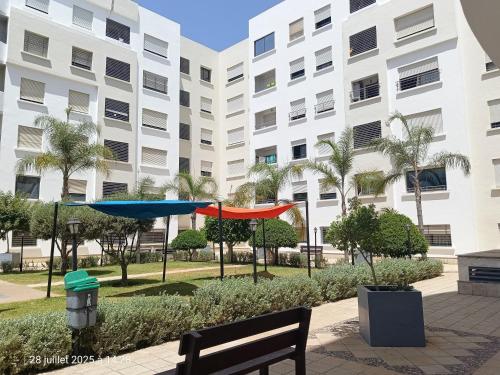 a building with two umbrellas in front of a park at Appart Haut Standing, Très Calm à Nouaceur, Parking, Piscine, à 4min de l'Aéroport in Casablanca