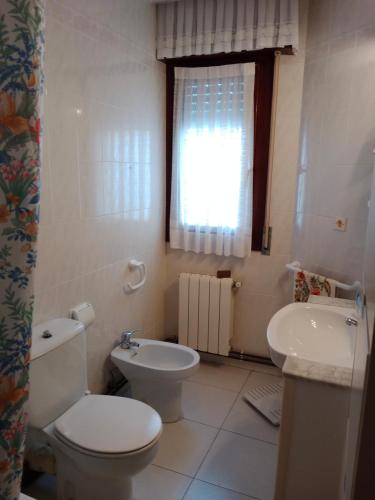 a white bathroom with a toilet and a sink at Noja 1 in Noja