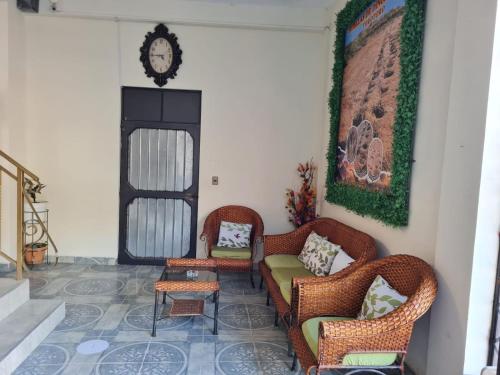 a living room with chairs and a clock on the wall at Hostal La Extincion in Torotoro