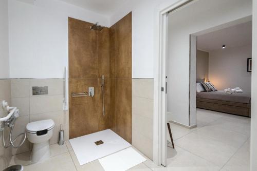 a bathroom with a shower with a toilet and a bed at Hotel Vicolo Aperta in Trapani