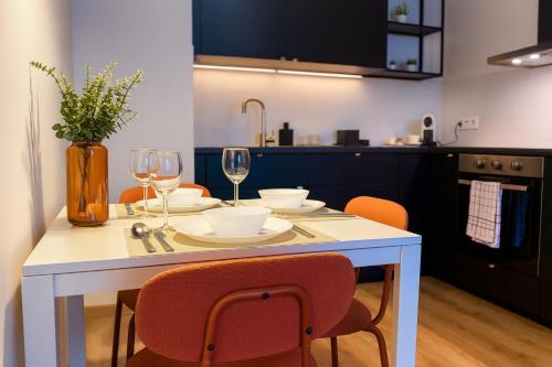 a kitchen with a white table with chairs and wine glasses at nook I Airport apartments in Bratislava