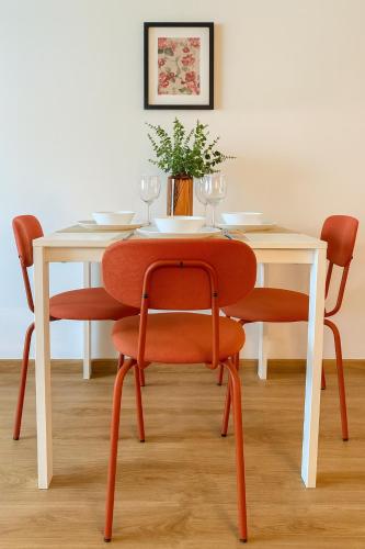 a table with orange chairs and a white table with glasses at nook I Airport apartments in Bratislava