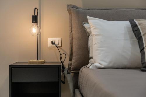 a bed with a white pillow and a lamp on a table at Hotel Vicolo Aperta in Trapani