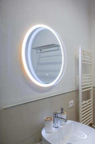 a bathroom with a round mirror above a sink at Hotel Vicolo Aperta in Trapani