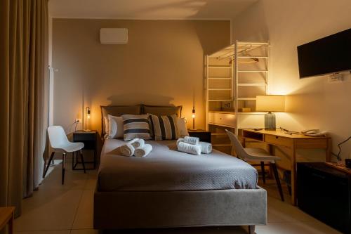 a bedroom with a bed with a desk and chairs at Hotel Vicolo Aperta in Trapani