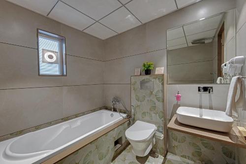 a bathroom with a tub and a toilet and a sink at CLAY Royal Comfort by SOIL TO SOUL in Dwarka