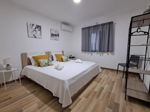 a bedroom with a white bed and a wooden floor at Casa do Sardão in Sardoal