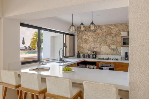 a kitchen with a island with chairs and a counter at Casa Playa Cozumel - Luxury Beachfront Villa in Cozumel