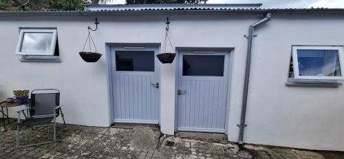 a white house with two doors and a table at Dairy Cottage Courtyard accommodation in Bunmahon