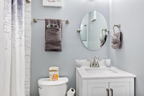 a white bathroom with a sink and a mirror at Spacious 4BR House Sleeps 9 Outdoor Lounge with Fire Pit plus Games in Raleigh