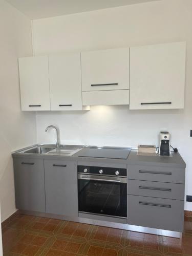 a kitchen with a stove and a sink and white cabinets at CASA STAVELLO in Sernio