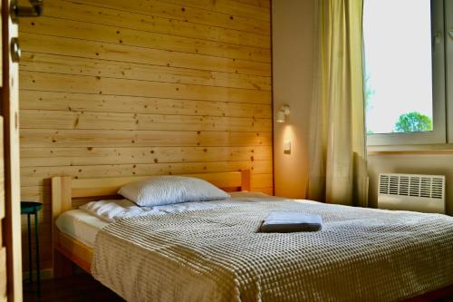 a bedroom with a bed with a wooden wall at Żubrowe Sioło - dom w naturze - najładniejsze widoki - nowość in Białowieża