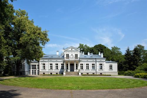 a large white house with a lawn in front at Palac i Loft Ojrzanów in Ojrzanów