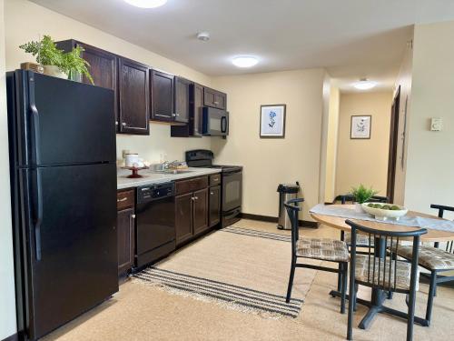 a kitchen with a black refrigerator and a table at Broad Street Commons in Plattsburgh