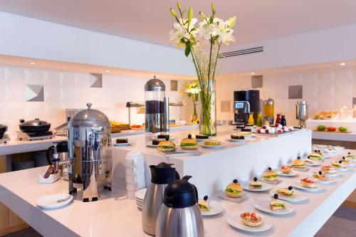 Una línea de buffet con platos de comida y flores. en NH San Luis Potosí, en San Luis Potosí