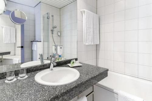 a white bathroom with a sink and a shower at NH Weinheim in Weinheim