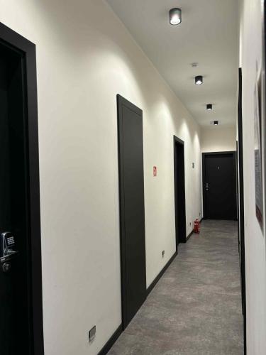 a hallway with black doors and white walls at "Przy Rynku" pokoje z prywatnymi łazienkami in Gliwice