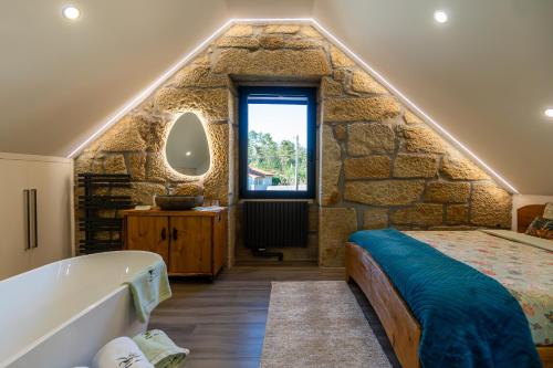 a stone walled bedroom with a bed and a bath tub at Casa Pinto Oliveira in Bodiosa