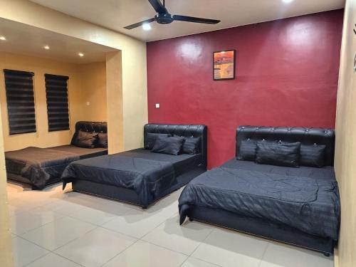 a room with two beds and a red wall at SR Kampar 2-Storey LANDED HOMESTAY in Kampar