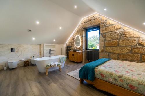 a bedroom with a stone wall and a bed and a tub at Casa Pinto Oliveira in Bodiosa