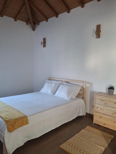 a bedroom with a large white bed and a wooden dresser at Casa d Amelinha in Gatão