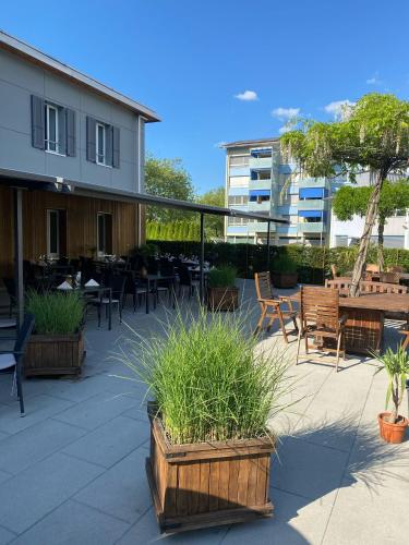 a patio with tables and chairs and plants and a building at Guesthouse Meitschi Thun - contactless self check-in in Thun